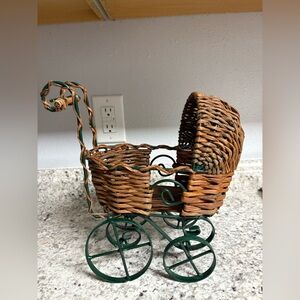 Vintage wicker doll carriage/stroller with a green iron frame/wheels.
